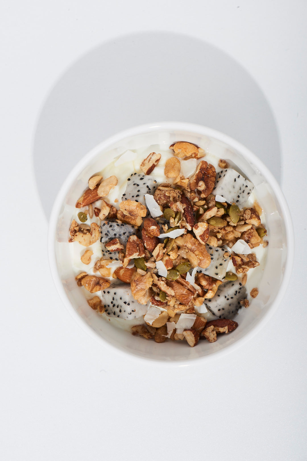 Yogurt bowl with granola, nuts, and seeds on a white background