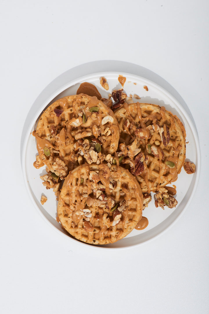 Round plate with cookies topped with nuts on a white background