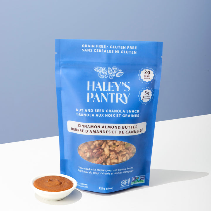 Haley's Pantry cinnamon almond butter snack package with a small bowl of the product on a light blue background