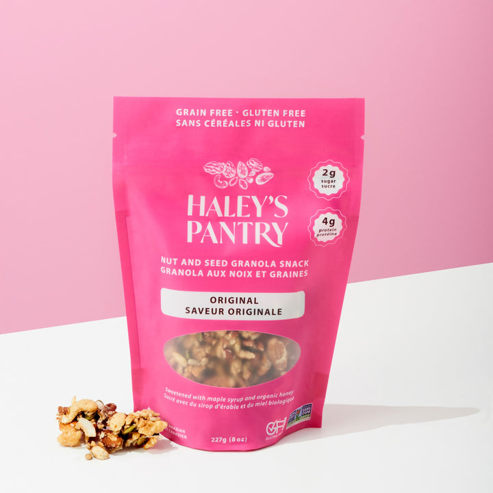 Pink package of Haley's Pantry nut and seed granola snack on a white surface with a pink background