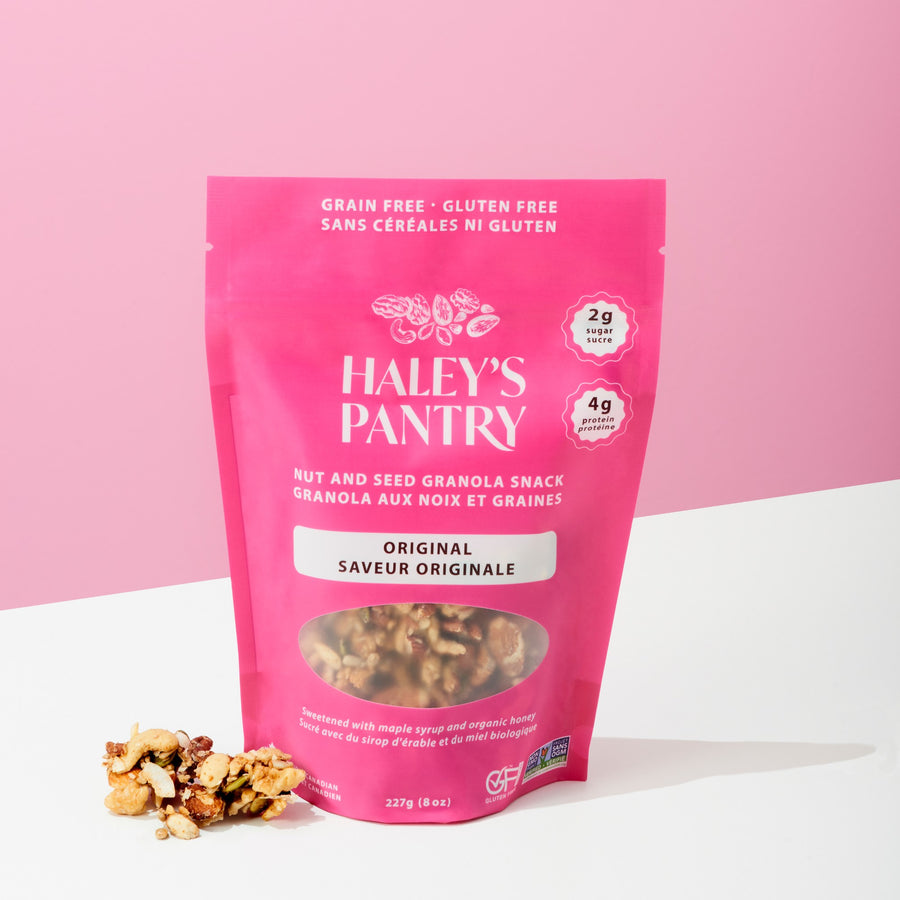 Pink package of Haley's Pantry nut and seed granola snack on a white surface with a pink background